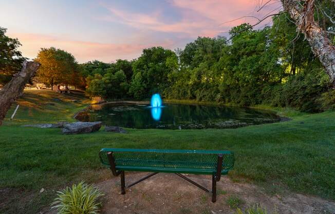 a bench in front of a pond with a blue fountain