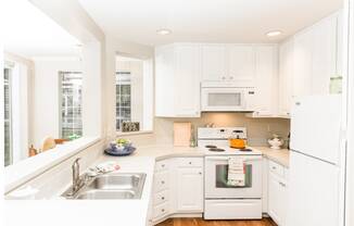 a white kitchen with a sink and a window