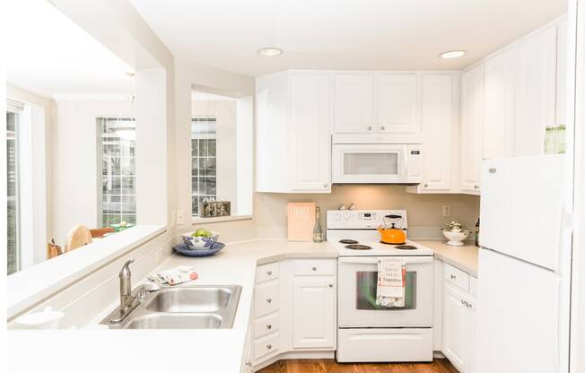 a white kitchen with a sink and a window