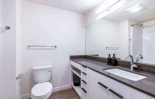 a bathroom with white walls and a large mirror at Marina Square, Bremerton