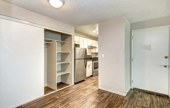 an empty room with a kitchen with a refrigerator and a closet