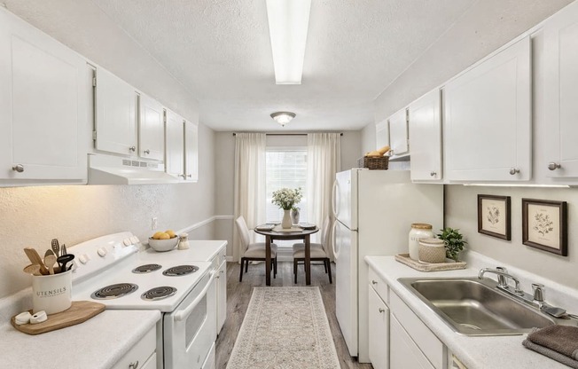 A kitchen with white cabinets and a stove top oven.
