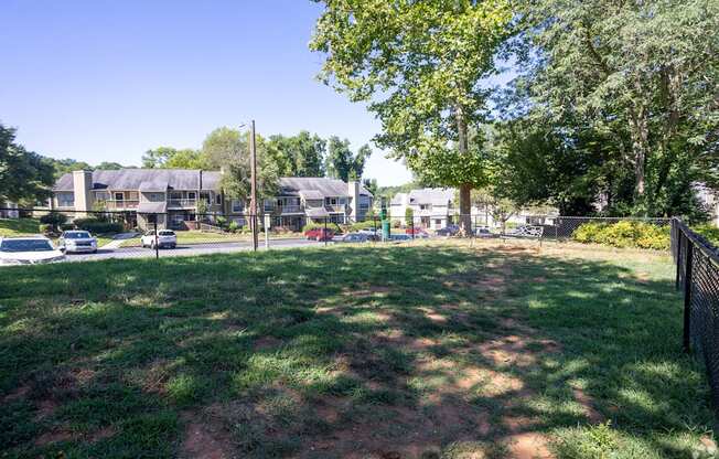 a yard with houses in the background and trees