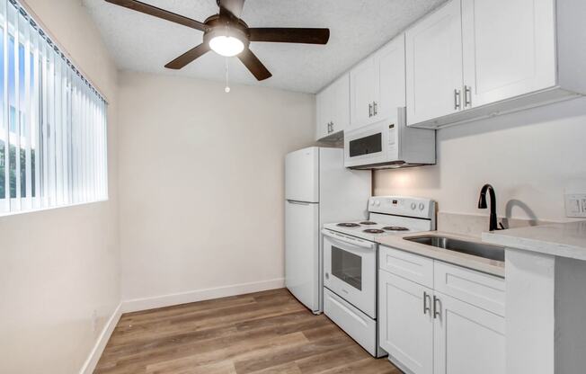 a kitchen with white appliances and a ceiling fan