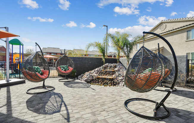 Four hanging chairs are placed on a patio.