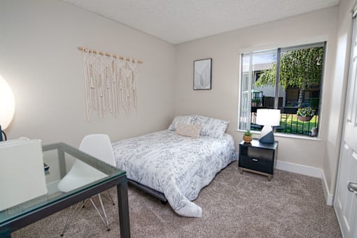 Model apartment spare bedroom with a bed and a desk and a window