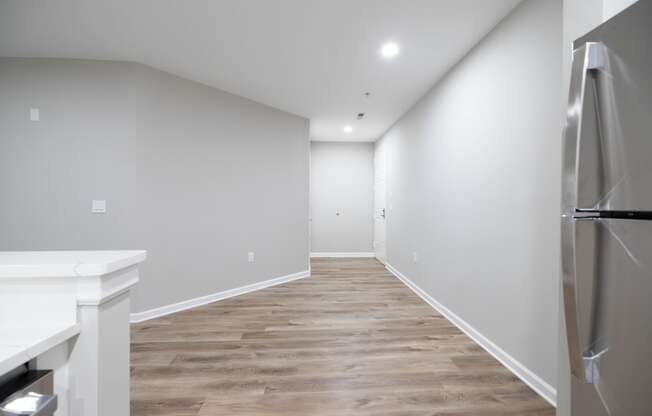 a renovated kitchen with white walls and wood flooring and a stainless steel refrigerator