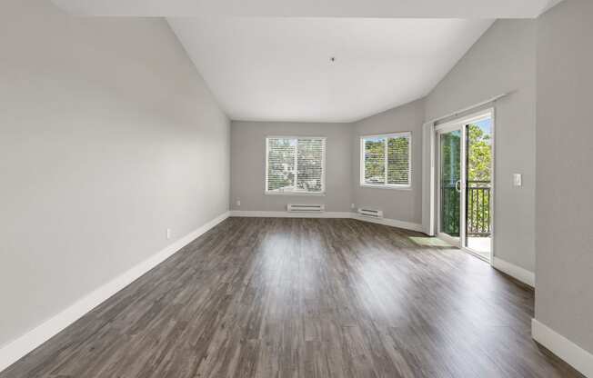 an empty living room with wood floors and a door to a balcony