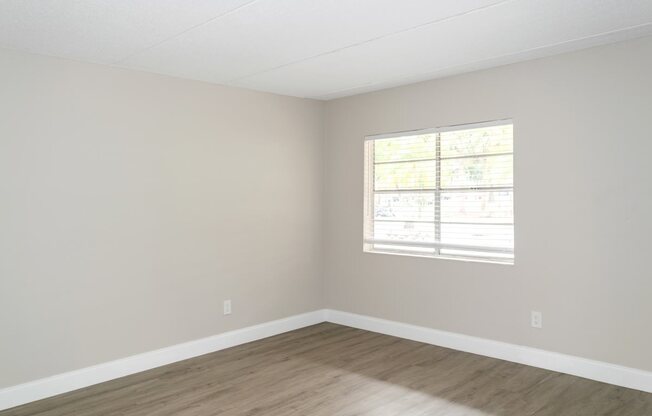 an empty room with a window and wooden floors