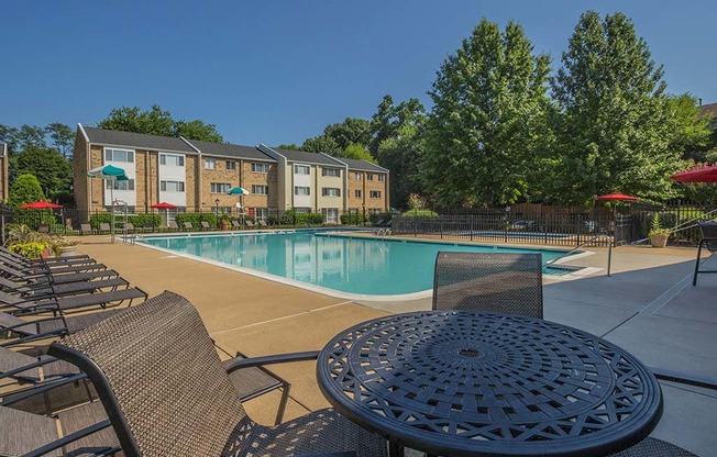 Outdoor table seating area with lounge chairs by the pool at Tysons Glen Apartments and Townhomes, Falls Church