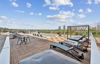A rooftop patio with a table and chairs overlooking a city skyline.