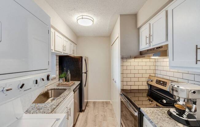 A kitchen with white cabinets and a black fridge.