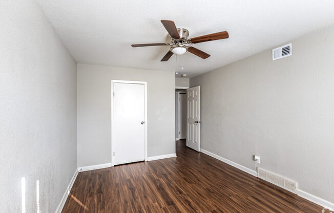 A room with a ceiling fan and wooden floors.