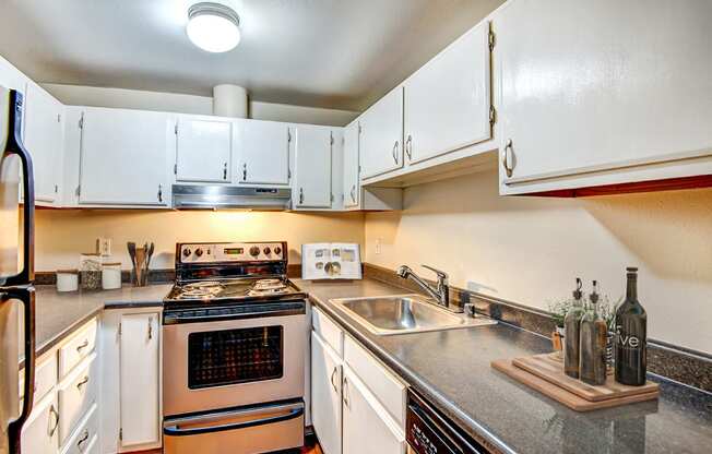 the kitchen is equipped with stainless steel appliances and white cabinets