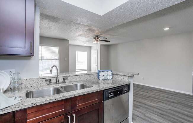 A kitchen with a sink, stove, and a fan.