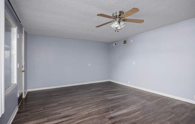 A room with a ceiling fan and wooden flooring.