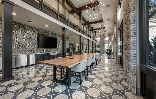 a communal table in a lobby with chairs and a television