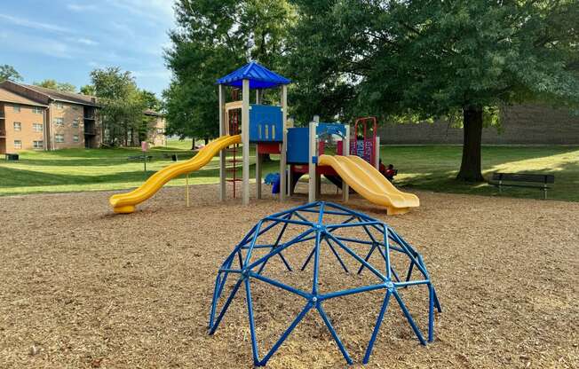 Playground with a blue spider bars in front of a playset at Deer Park Apartments, Randallstown, MD