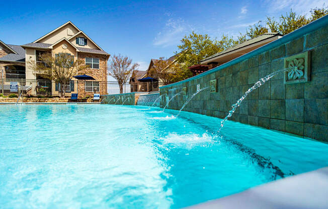 a large pool with a water feature in front of a house
