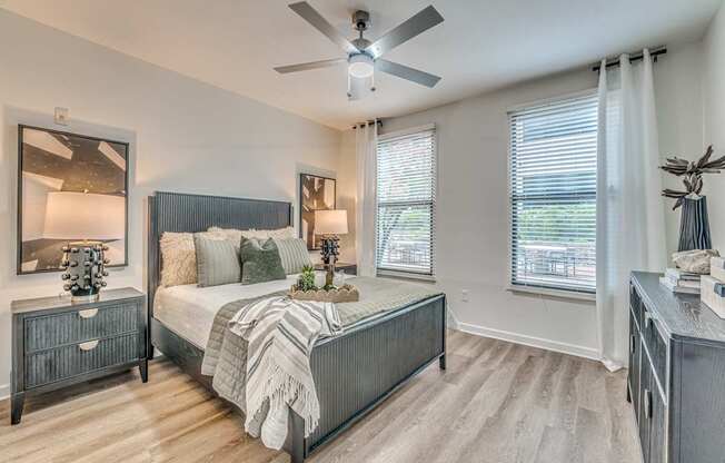 A bedroom with a large bed, a nightstand, and a ceiling fan.