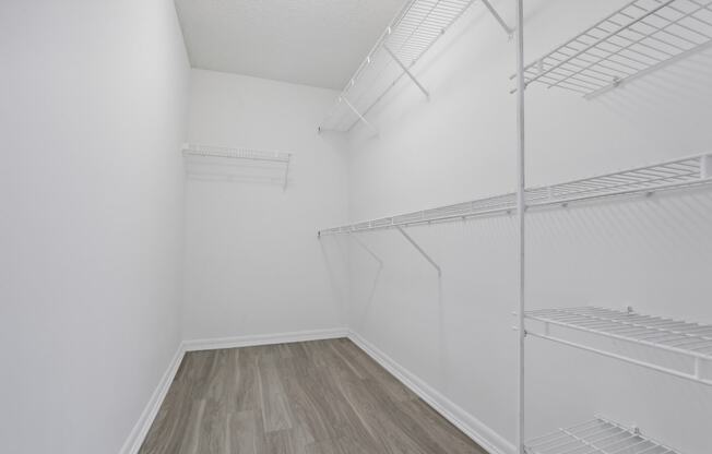 an empty room with white walls and wood flooring and a white closet with shelves at Pembroke Pines Landings, Pembroke Pines, Florida