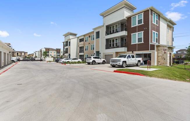 A parking lot in front of a multi-story apartment building.