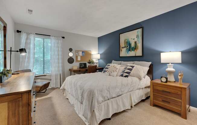 A bedroom with a large bed and a painting on the wall.