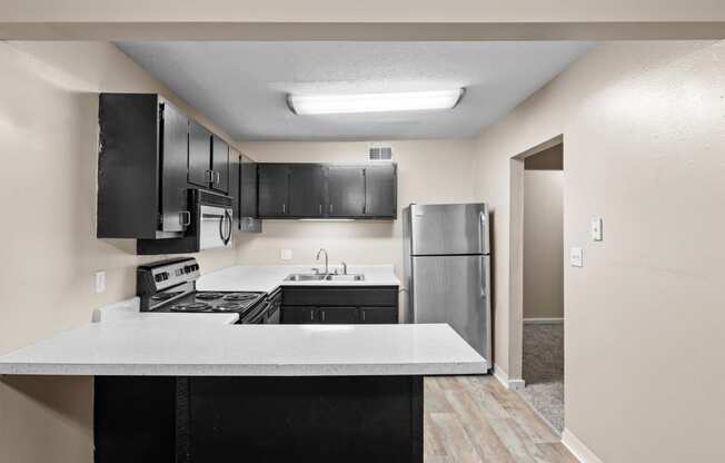 an empty kitchen with black cabinets and a stainless steel refrigerator