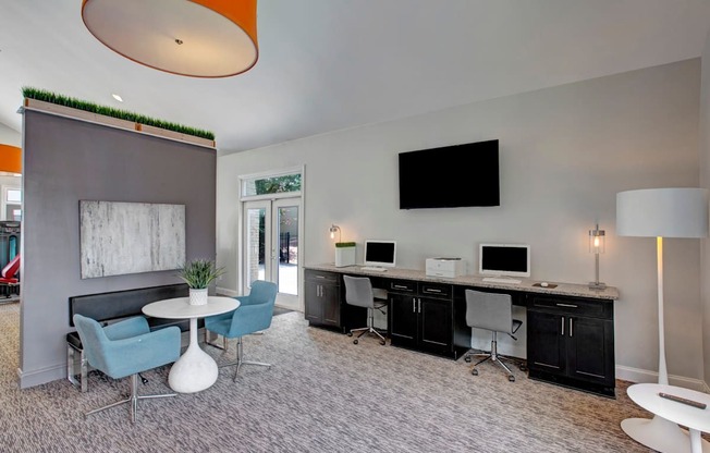 A modern office space with a grey carpet, a white table, and a TV mounted on the wall. at Dunwoody Glen, Atlanta, GA