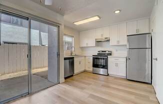 A kitchen with white cabinets and a wooden floor.