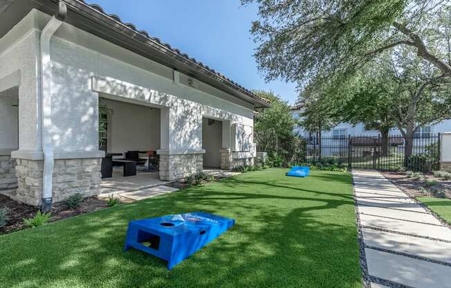 A blue plastic container is placed on a green lawn in front of a house.