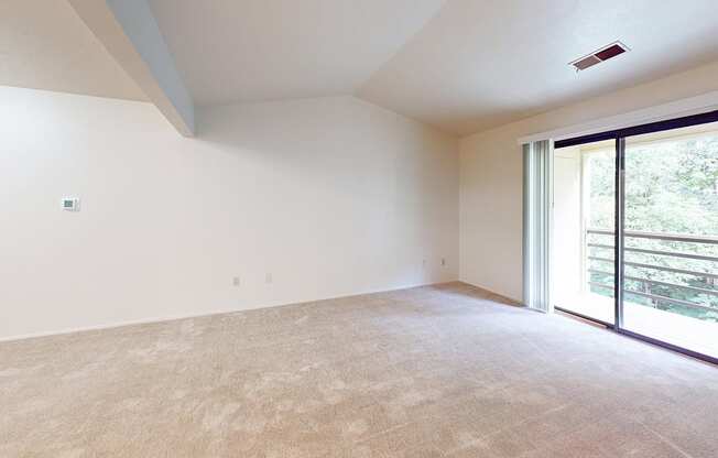 A living room with a high ceiling and a carpeted floor and sliding glass doors at Emerald Park Apartments, Michigan