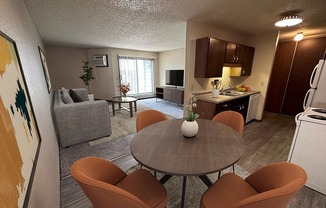 a living room with a table and chairs and a kitchen in the background