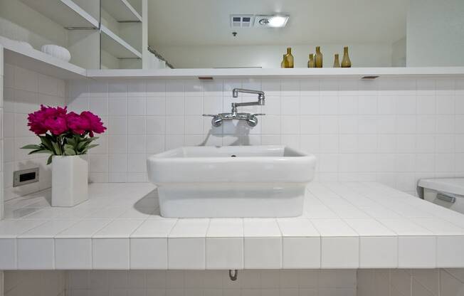 a white bathroom with a sink and a vase of flowers