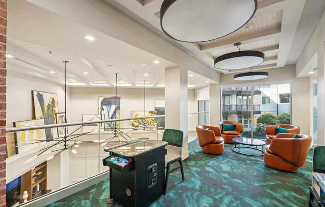 A room with orange chairs and a glass table with a black box on it.