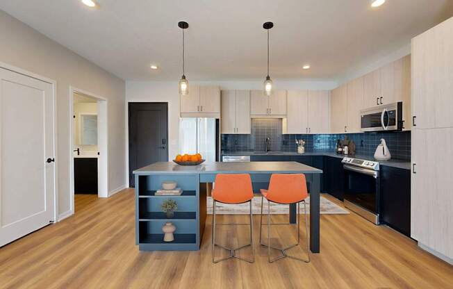 A kitchen with a blue island and orange chairs.