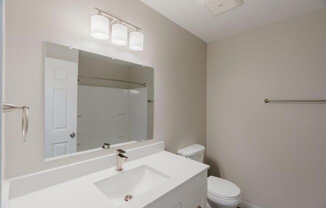 A white bathroom with a toilet, sink, and mirror.