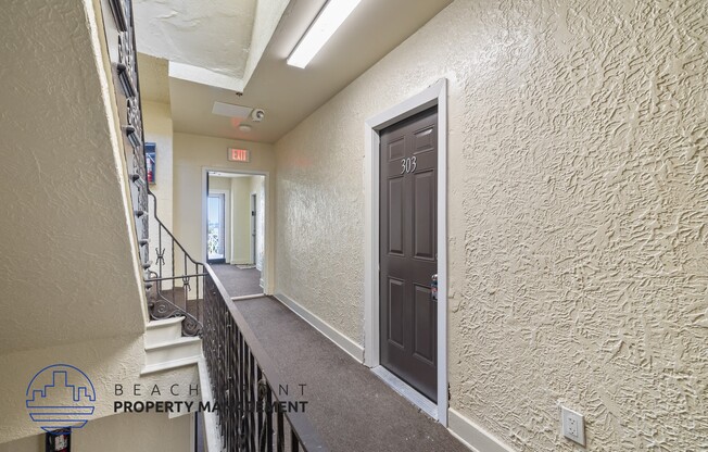 the upstairs hallway of a building with a brown door and stairs