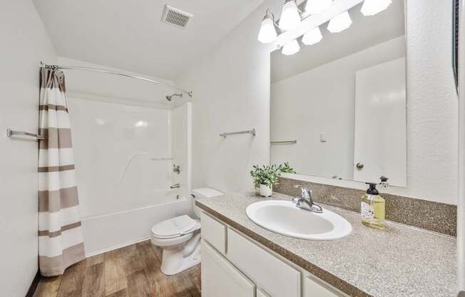 A bathroom with a toilet, sink, and mirror.