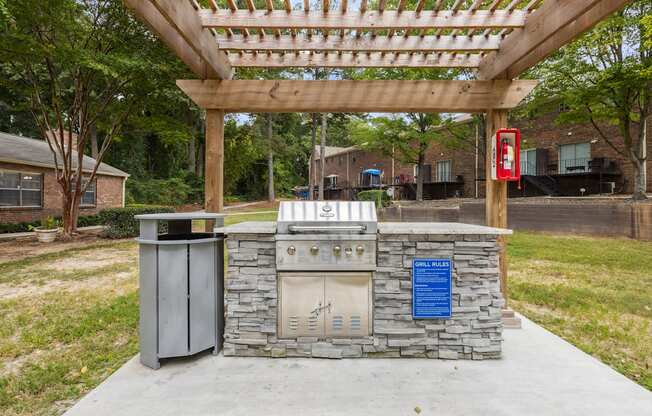 a covered patio with a barbecue grill and a trash can