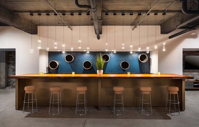a bar with stools in front of a blue wall with pendant lights