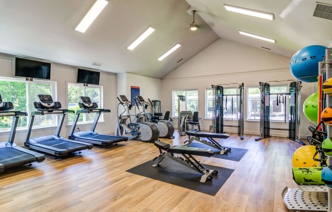 a gym with cardio equipment and weights on a wooden floor