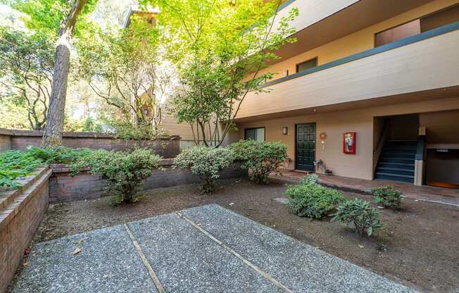 A courtyard with a gravel ground and a tree in front of a building.