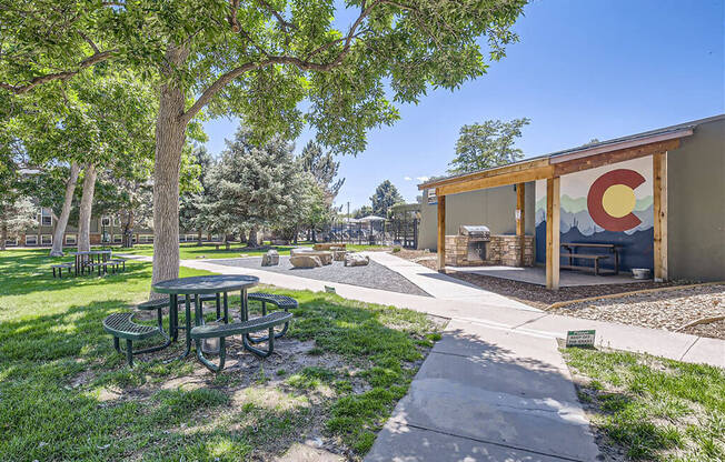 a pavilion with picnic tables and a tree next to a building