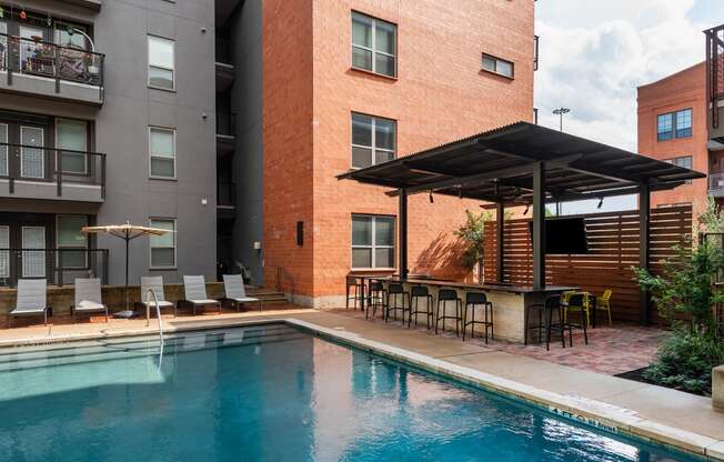 a swimming pool with chairs and a bar next to a building