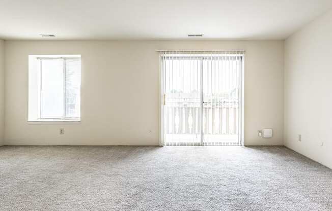 an empty living room with a window and a carpeted floor