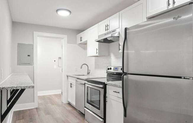 A modern kitchen with stainless steel appliances and white cabinetry.