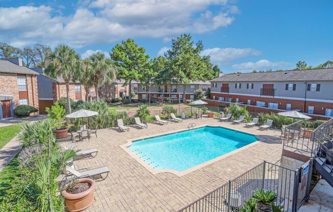 A pool surrounded by a fence and lounge trees at Magnolia Apartments in Shreveport, LA