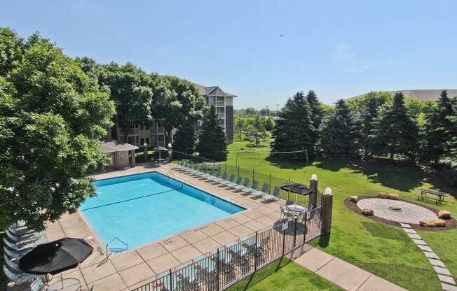 a swimming pool with a fence around it and a lawn with trees