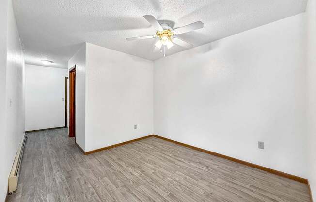 A room with a ceiling fan and a wooden floor.